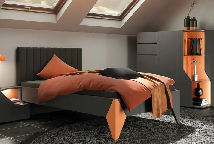 Schlafzimmer unterm Dach mit grauem Bett und orangefarbener Bettwäsche, links Nachttisch mit Lampe und Leuchtnische, rechts Kleiderschrank mit offenen Fächern unter zwei Dachfenstern.